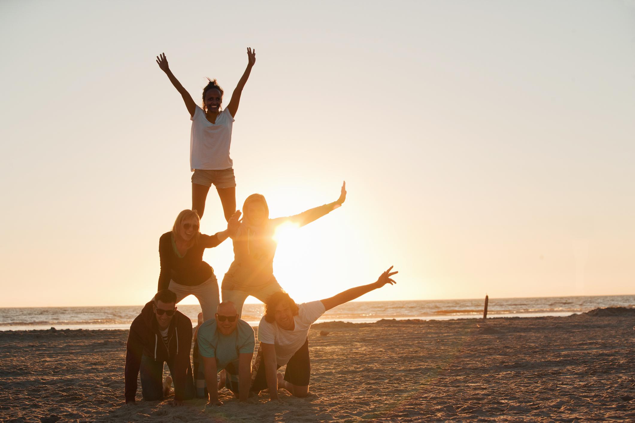 Five people stacked into a pyramid on a beach